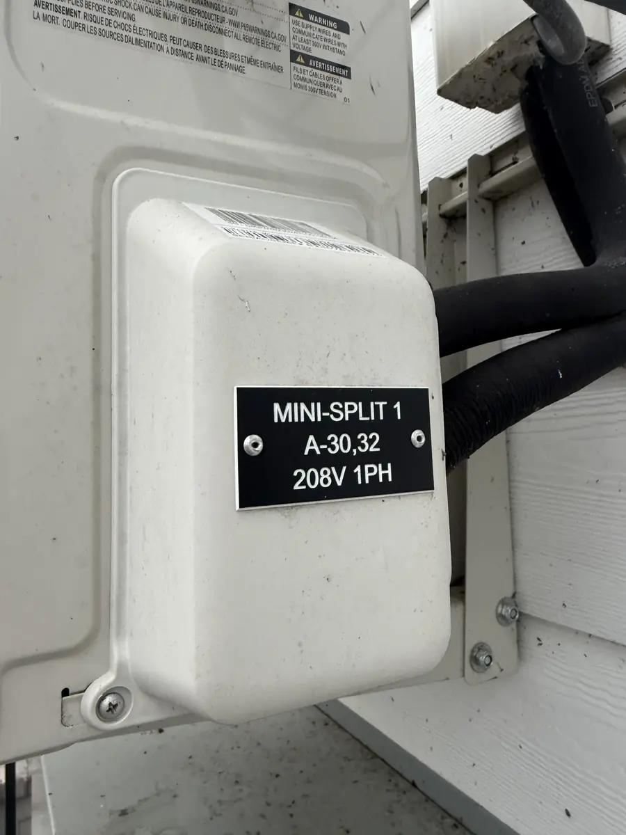 Black equipment tag reading MINI-SPLIT 1 A-30,32 208V 1PH on an HVAC disconnect box