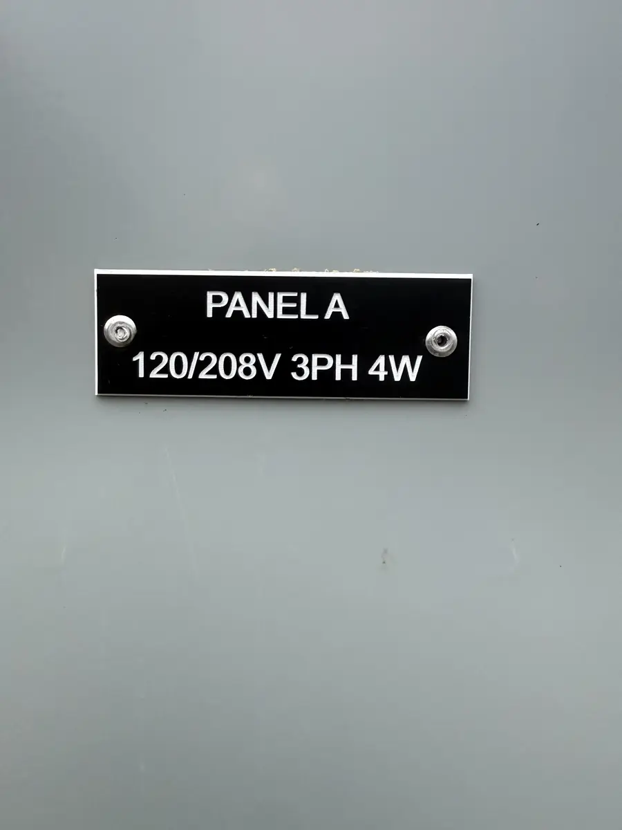 Black phenolic tag engraved PANEL A 120/208V 3PH 4W screwed to a gray panelboard